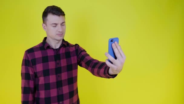 Hombre guapo se fotografía a sí mismo en una cámara selfie smartphone y sonríe — Vídeos de Stock