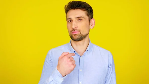 Sakallı adam sarı arka planda kopyalanmış bir parmak gösteriyor.