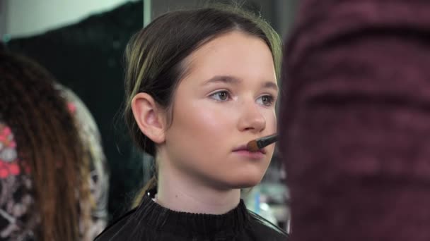 Make-up umělec aplikuje prášek na obličej štětcem na dospívající dívku v salonu — Stock video