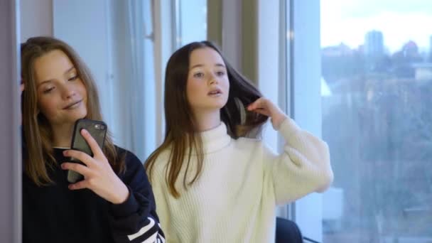 Meninas fotografar-se no espelho em um smartphone, pose e grimace — Vídeo de Stock