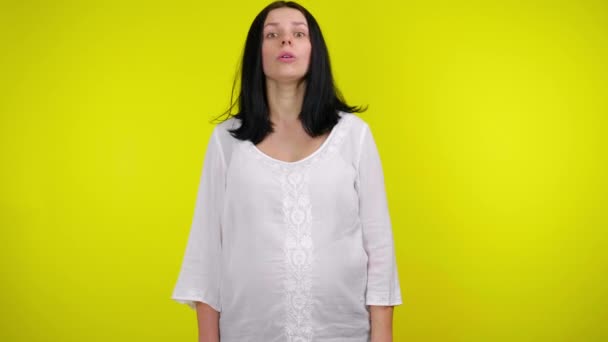 Молода вагітна жінка каже "так" і тремтить головою на жовтому тлі — стокове відео
