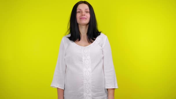 Beyaz bluzlu, siyah saçlı hamile kadın evet diyor, başını sallıyor ve gülümsüyor. — Stok video