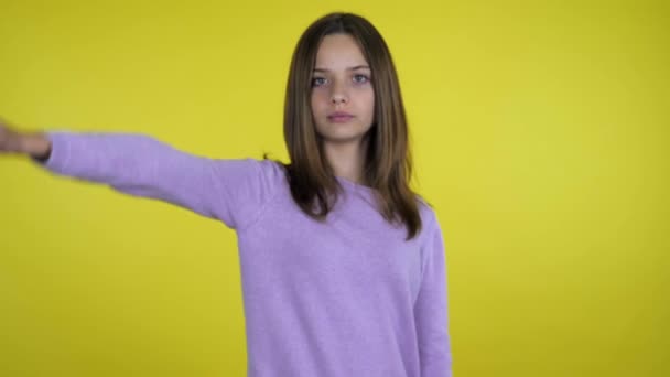 핑크 스웨터를 입은 진지 한 십 대 소녀는 노란 배경 이 싫어 보인다 — 비디오