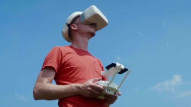 Adam bir kuadrokopteri uzaktan kumandayla kontrol ediyor.