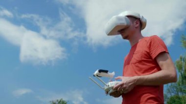 Adam bir kuadrokopteri uzaktan kumandayla kontrol ediyor.