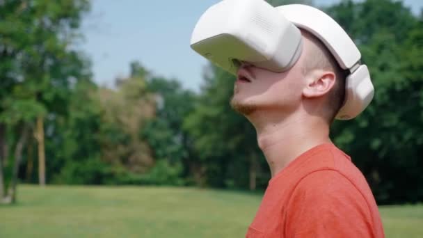 El hombre en un casco de realidad virtual gira la cabeza hacia la izquierda y hacia arriba — Vídeos de Stock