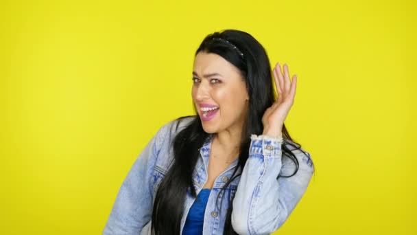 Frau hört nicht, hebt die Hand ans Ohr auf gelbem Hintergrund mit Kopierraum — Stockvideo