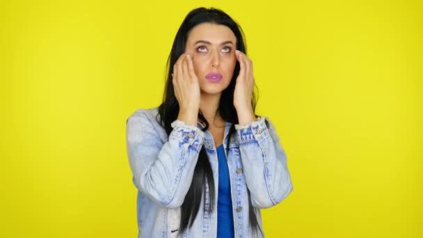 Frau massiert den Bereich unter ihren Augen auf gelbem Hintergrund mit Kopierraum — Stockvideo