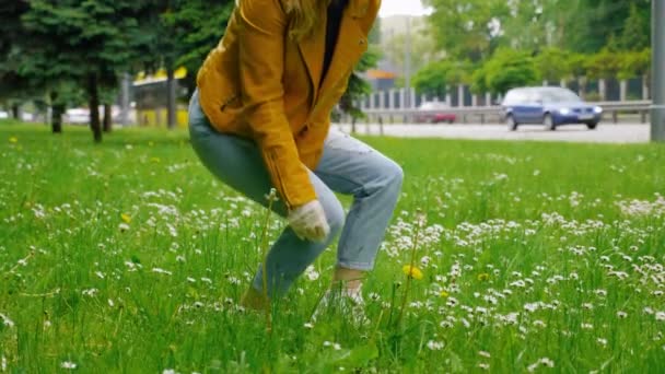 Kvinna i svart mask plockar en gul blomma och sniffar genom en skyddande mask — Stockvideo