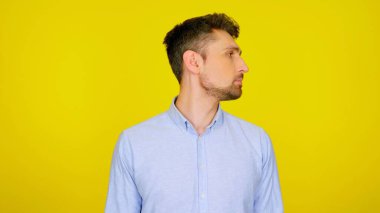 Yakışıklı sakallı adam, sarı arka planda kopyalanmış bir yere bakıyor.