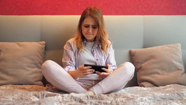 Mujer emocionalmente juega un videojuego en un teléfono inteligente, pierde y se molesta — Vídeos de Stock