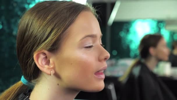 Closeup teenager girl with makeup in beauty salon, sitting on chair and smiling — Stock Video