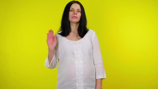 Młoda ciężarna kobieta podnosi rękę z dłonią przed kamerą i mówi stop — Wideo stockowe