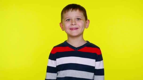 Kleine jongen lacht op een gele achtergrond met kopieerruimte — Stockvideo