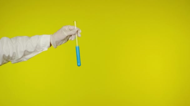 La protección manual del guante de látex muestra un tubo de vidrio con la sustancia azul claro — Vídeo de stock