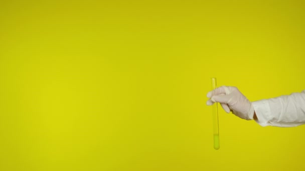 Ruka v latexové rukavici ochrana ukazuje skleněnou trubici se žlutou látkou — Stock video