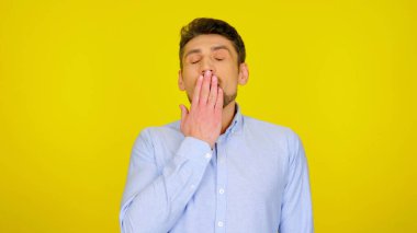 İnsan ağzını kapayarak esniyor. Avuç içi sarı arka planda, kopyalama alanı var.