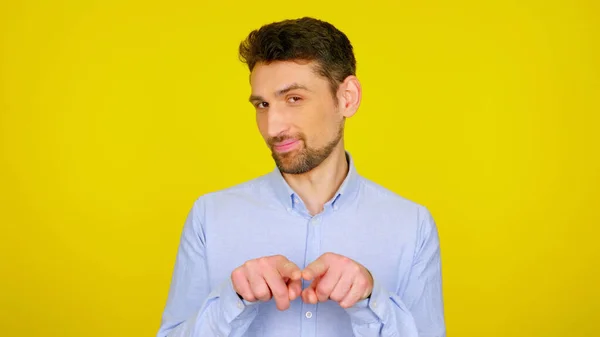 Homem flerta e mostra gestos em um fundo amarelo com copyspace — Fotografia de Stock