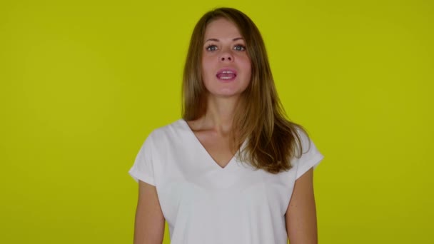 Frau im weißen T-Shirt blickt in die Kamera und sagt JA auf gelbem Hintergrund — Stockvideo