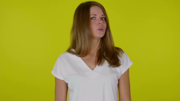 Mulher em uma camiseta branca olha para a câmera e diz NÃO em um fundo amarelo — Vídeo de Stock