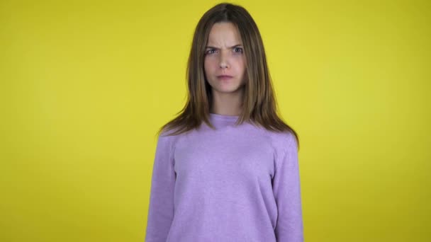 Boos tiener meisje in een roze trui lachen op een gele achtergrond — Stockvideo