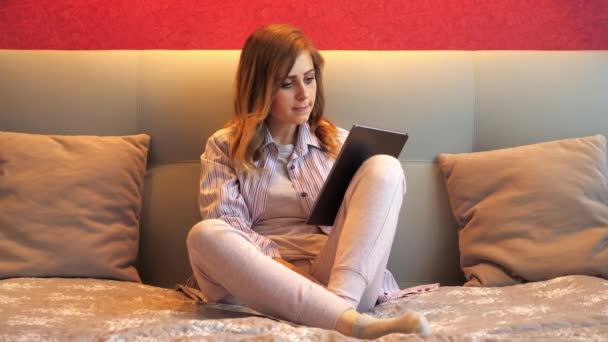 Femme avec une tablette à la main, regarde les nouvelles et est choquée par l'information — Video