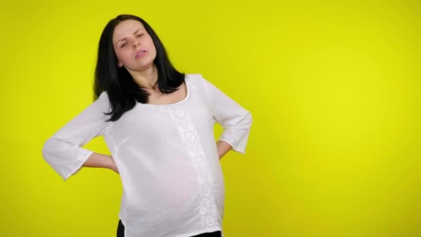 Gravid kvinna masserar ryggsmärta, håller magen med handen, lider av smärta — Stockvideo