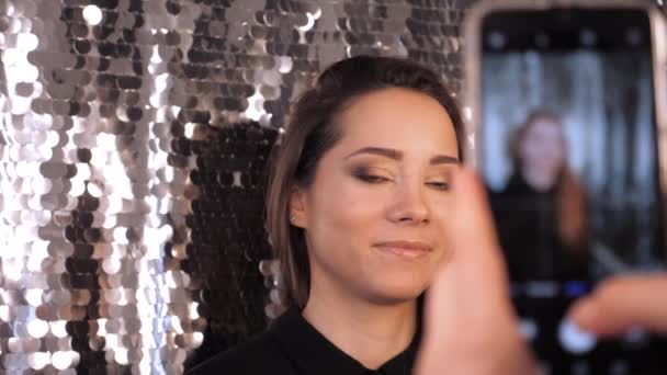 Дівчина з красивим макіяжем позує за мобільним фотографом і посміхається — стокове відео