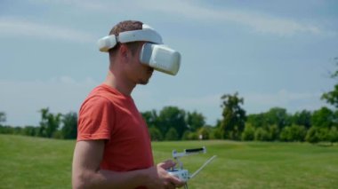 Adam bir kuadrokopteri uzaktan kumandayla kontrol ediyor.