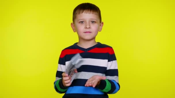 Багатий маленький хлопчик тримає багато грошей в руці і стукає в іншу руку — стокове відео
