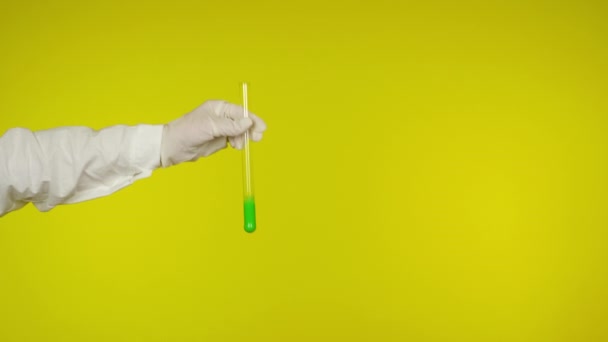 Ruka v latexové rukavici ochrana ukazuje skleněnou trubici se světle zelenou látkou — Stock video