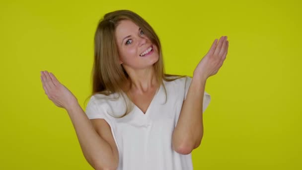 A fehér pólós nő leveszi a tenyerét az arcáról és sárga alapon mosolyog. — Stock videók