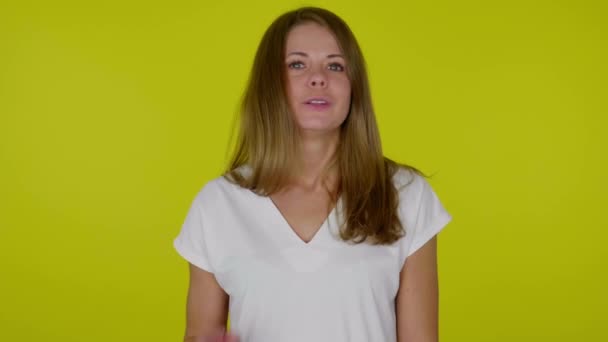 Woman looks at the camera, says NO, raises hand, shows palm on yellow background — Stock Video