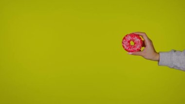 Kadın eli kırmızı lezzetli ve taze bir çörek tutuyor, sarı arka planda.