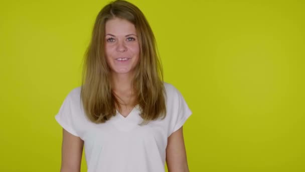 Mujer alegre en una camiseta blanca riendo sobre un fondo amarillo — Vídeos de Stock