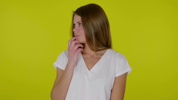 Vrouw in een wit T-shirt kijkt om zich heen en weet niet wat ze moet kiezen — Stockvideo