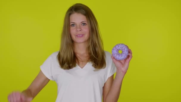 Woman raises hand with a blue donuts, shows dislike, shakes hand and grimaces — Stock Video