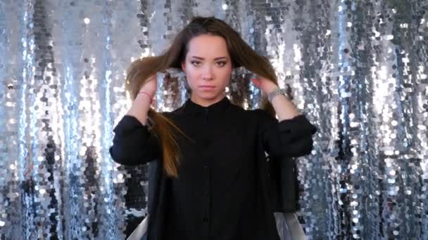 Жінка сидить на стільці позує за камерою і вирівнює волосся рукою — стокове відео