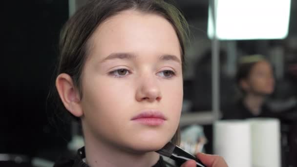 Makeup artist applies foundation on face with brush to teenager girl in salon — Stock Video