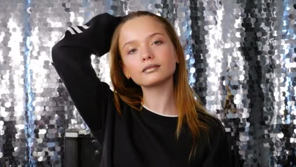 Teenager dívka s krásnou make-up narovnává vlasy s rukou, pózuje a usmívá — Stock video