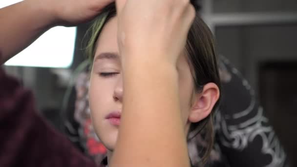 Maquillaje artista aplica fundación en la cara con cepillo a la chica adolescente en el salón — Vídeos de Stock