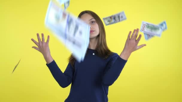 Rijk tiener meisje kotst omhoog veel geld en glimlacht op gele achtergrond — Stockvideo