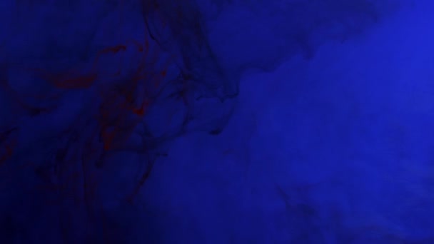 Inchiostro rosso scuro che si mescola in acqua, turbinando dolcemente sott'acqua su sfondo blu — Video Stock