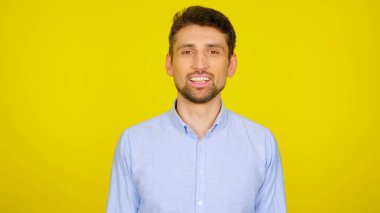 Açık mavi gömlekli yakışıklı sakallı adam gülümsüyor..