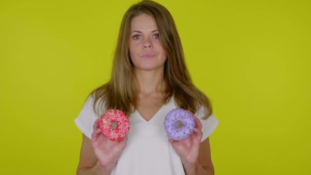 Serious woman in a white T-shirt raises hands with blue and red donuts — Stock Video