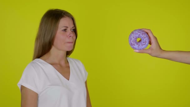 Mulher com fome em uma dieta olha para o donut, lambe e morde lábios, quer comer — Vídeo de Stock