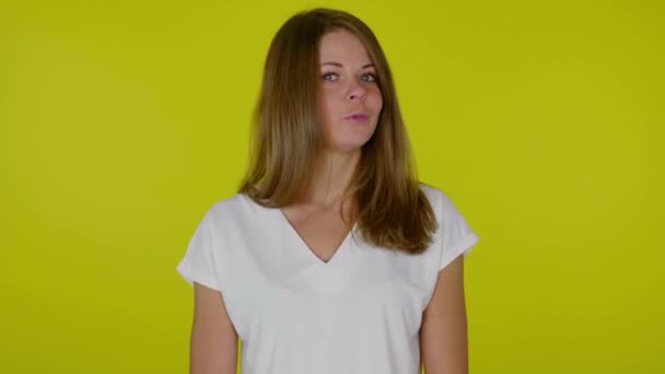 Woman in a white T-shirt looks at the camera and says NO on a yellow background — Stock Video