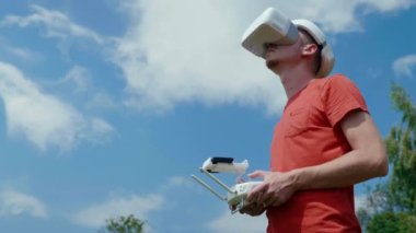 Adam bir kuadrokopteri uzaktan kumandayla kontrol ediyor.