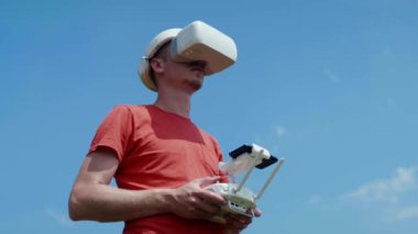 Adam bir kuadrokopteri uzaktan kumandayla kontrol ediyor.