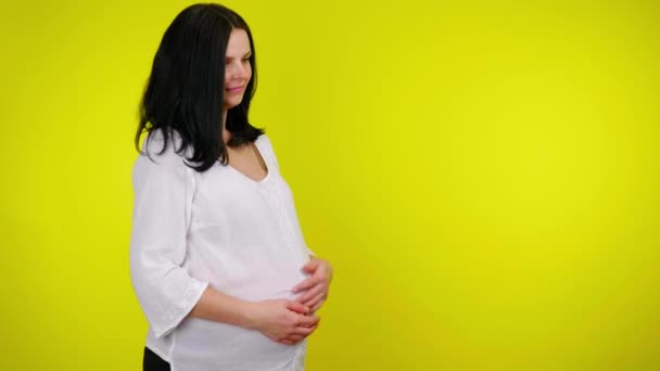 Молодая беременная женщина массирует живот, ребенок толкает и двигается — стоковое видео